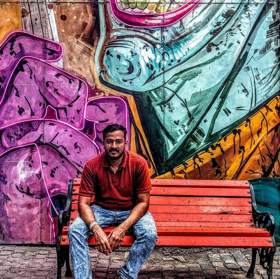 Shubham Raj seated in front of a colorful mural